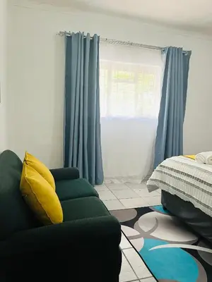 a living room with a green couch and blue curtains at Hlatsi Bushview Apartments & Safaris in Hazyview