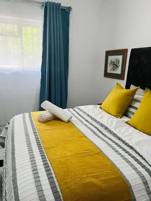 a bedroom with a large bed with yellow pillows at Hlatsi Bushview Apartments & Safaris in Hazyview
