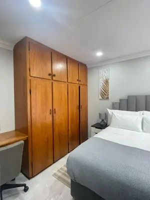 a bedroom with a bed and a wooden cabinet at Omega 8 in Polokwane