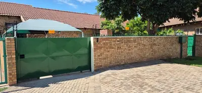 a fence with a green gate in front of a house at Omega 8 in Polokwane