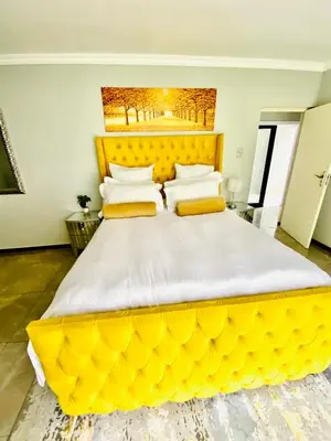 a large bed with a large yellow head board at ALIMU villa Mbombela in Nelspruit