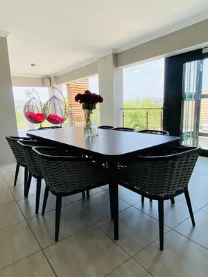 a dining room table with chairs and a vase of flowers at ALIMU villa Mbombela in Nelspruit