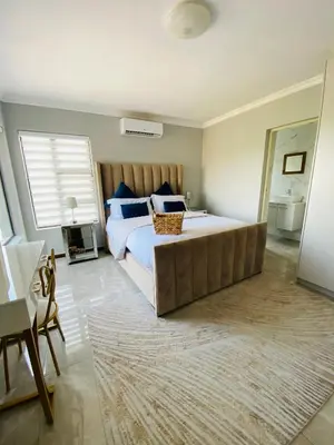 a bedroom with a large bed with a large window at ALIMU villa Mbombela in Nelspruit