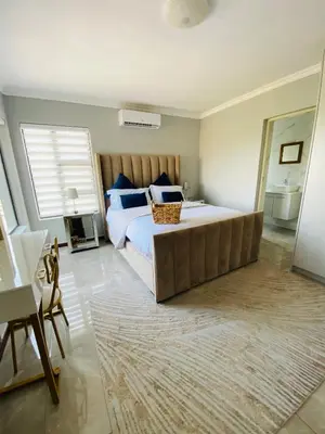 a bedroom with a large bed with blue pillows at ALIMU villa Mbombela in Nelspruit