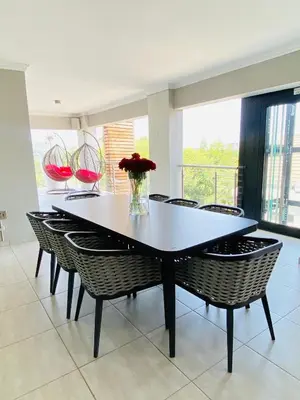 a dining room table with chairs and a vase of flowers at ALIMU villa Mbombela in Nelspruit