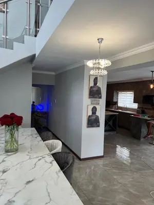 a living room with a table and a staircase at ALIMU villa Mbombela in Nelspruit