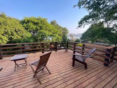 a wooden deck with two chairs and a table at Heart Of The Cosmos in Hartbeespoort