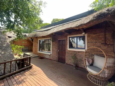 a house with a thatched roof and a deck at Heart Of The Cosmos in Hartbeespoort