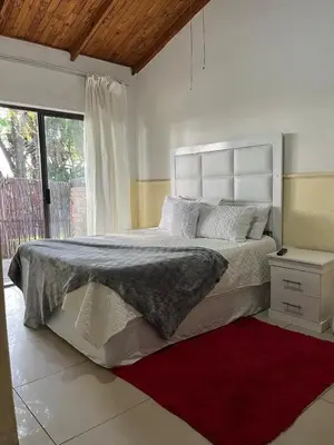 a white bedroom with a large bed and a red rug at Bluesky guest lodge in Pretoria