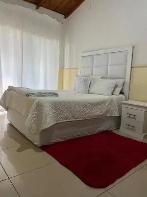 a white bedroom with a large bed and a red rug at Bluesky guest lodge in Pretoria