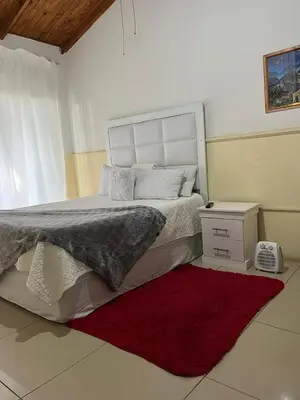 a bedroom with a large bed and a red rug at Bluesky guest lodge in Pretoria