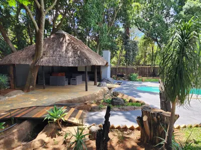 a small hut with a thatched roof next to a pool at Bluesky guest lodge in Pretoria