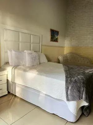 a bedroom with a large bed with white sheets and pillows at Bluesky guest lodge in Pretoria