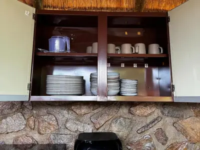 a cabinet with plates and mugs in it at Sundara Safaris