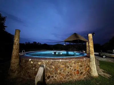 a swimming pool with a gazebo at night at Sundara Safaris