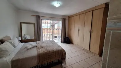 a bedroom with a bed and a large window at Secure house in complex near OR Thambo airport in Johannesburg