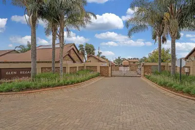 a driveway in front of a house with palm trees at Secure house in complex near OR Thambo airport in Johannesburg
