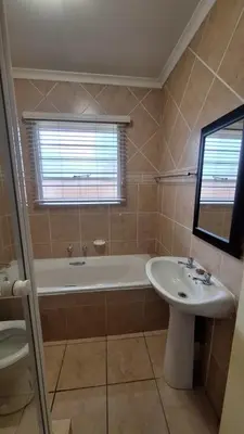 a bathroom with a tub and a sink and a bath tub at Secure house in complex near OR Thambo airport in Johannesburg