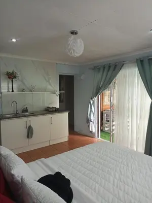 a bedroom with a white bed and a kitchen at The Tranquility Suite & Spa in Kempton Park