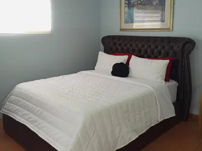 a bed with a black headboard and white pillows at The Tranquility Suite & Spa in Kempton Park