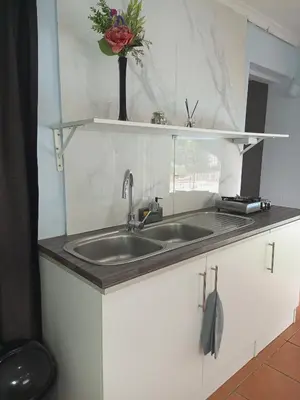 a kitchen counter with a sink and a vase of flowers at The Tranquility Suite & Spa in Kempton Park