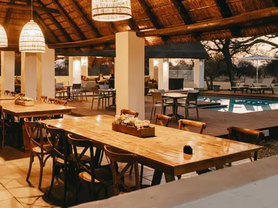 a restaurant with wooden tables and chairs and a pool at Tshikwalo Guest House in Hammanskraal