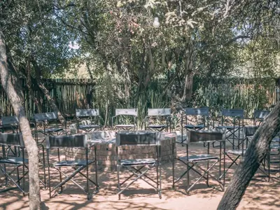 a group of chairs and tables under trees at Tshikwalo Guest House in Hammanskraal