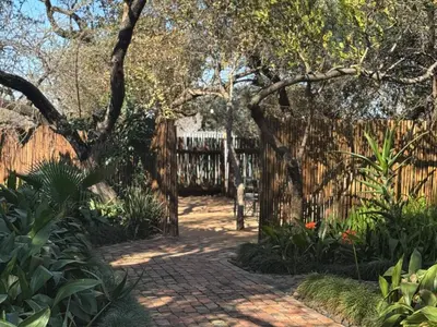 a garden with a wooden fence and a brick walkway at Tshikwalo Guest House in Hammanskraal