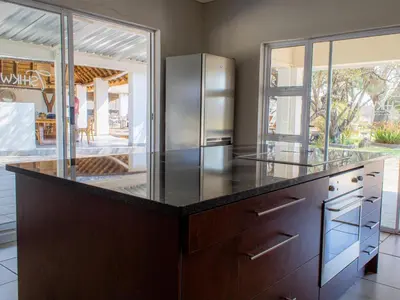 a kitchen with a large counter with a refrigerator at Tshikwalo Guest House in Hammanskraal
