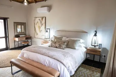 a bedroom with a large bed with two tables and a mirror at Landrift Villa in Phalaborwa