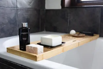 a wooden tray with a bottle of soap and cheese on a bath tub at Landrift Villa in Phalaborwa