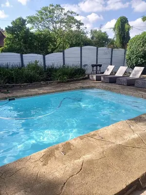a swimming pool with blue water in a yard at The Goshen Residence & Spa in Kempton Park