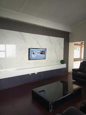 a living room with a large screen tv on a wall at The Goshen Residence & Spa in Kempton Park