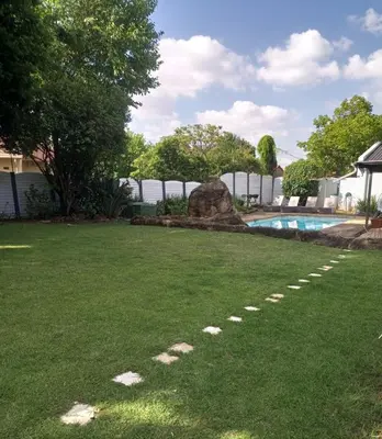 a backyard with a swimming pool and a grass yard at The Goshen Residence & Spa in Kempton Park