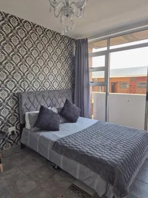 a bedroom with a bed and a large window at Elegant studio apartment in Hillcrest in Pretoria