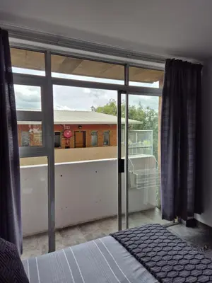 a bedroom with a view of a building through a window at Elegant studio apartment in Hillcrest in Pretoria