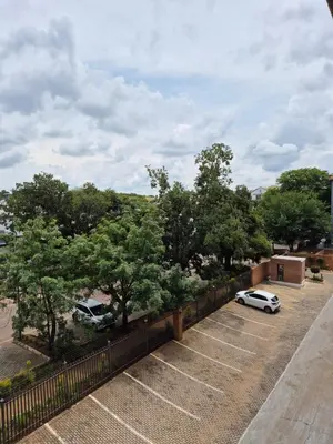 two cars parked in a parking lot with trees at Elegant studio apartment in Hillcrest in Pretoria