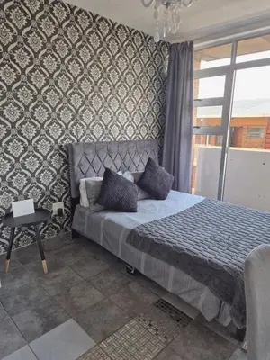 a bedroom with a bed with a patterned wall at Elegant studio apartment in Hillcrest in Pretoria