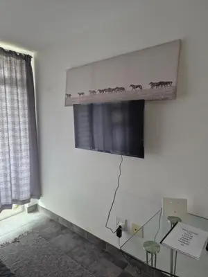 a room with a glass table and a shelf with horses on the wall at Elegant studio apartment in Hillcrest in Pretoria