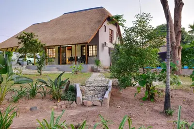 a small house with a thatched roof at Emathulini Holiday Home in Hazyview