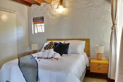 a bedroom with a bed with white sheets and pillows at Emathulini Holiday Home in Hazyview