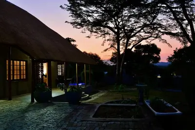 a building with a sunset in the background at Emathulini Holiday Home in Hazyview
