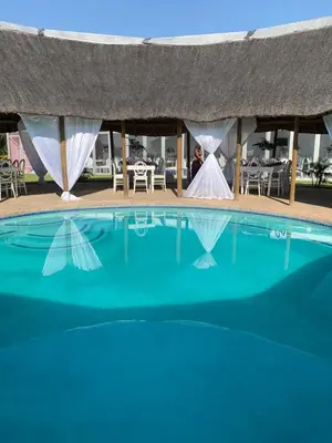 a bride and groom standing next to a swimming pool at Florencepalms resort & Spa in Marble Hall