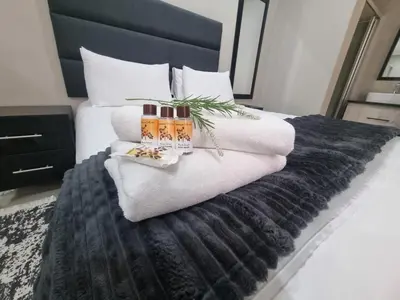 a bed with a black and white blanket and two candles at Airport Inn Bed and Breakfast in Kempton Park