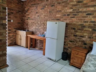 a kitchen with a white refrigerator and a wooden table at Airport Inn Bed and Breakfast in Kempton Park