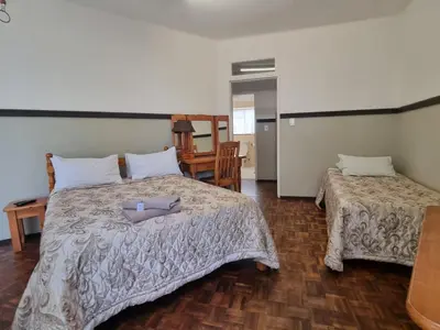 a bedroom with two beds and a table at Airport Inn Bed and Breakfast in Kempton Park