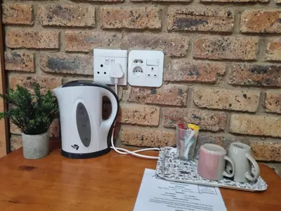 a table with a coffee maker and cups on it at Airport Inn Bed and Breakfast in Kempton Park