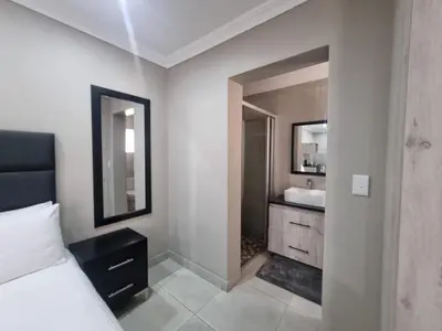 a bedroom with a bed and a sink and a mirror at Airport Inn Bed and Breakfast in Kempton Park