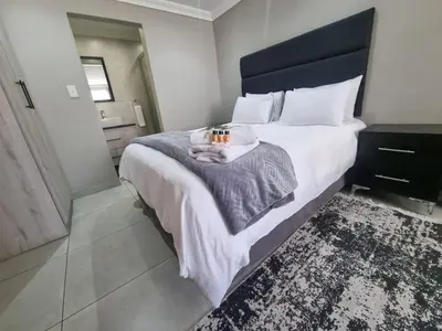 a bedroom with a large bed with a black headboard at Airport Inn Bed and Breakfast in Kempton Park