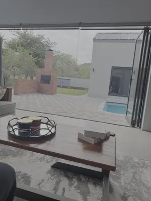 a room with a table and a view of a pool at Kambula Villa 374 Euphoria in Naboomspruit